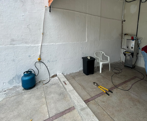 Ponto de gás instalado na parede com botijão e tubulação aparente